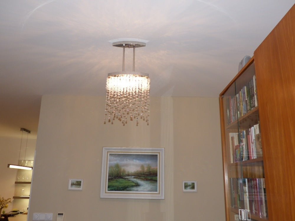 Plafonnier installé au plafond dans un salon, diffuse une lumière chatoyante au-dessus d'un tableau
