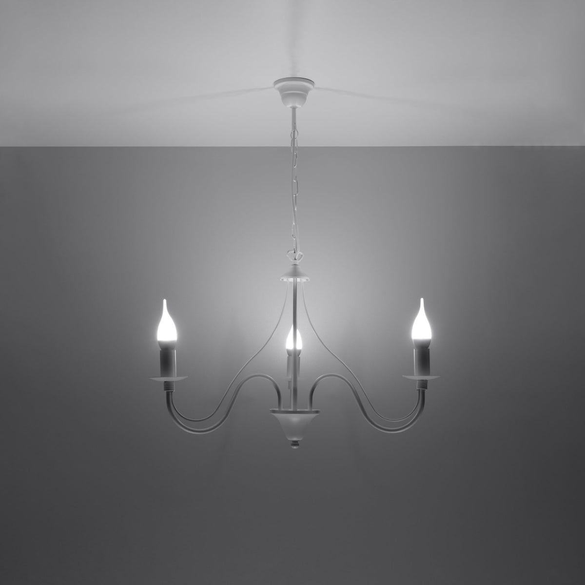 Mise en ambiance sombre du lustre blanc allumé, trois ampoules flamme diffusent une lumière blanche.