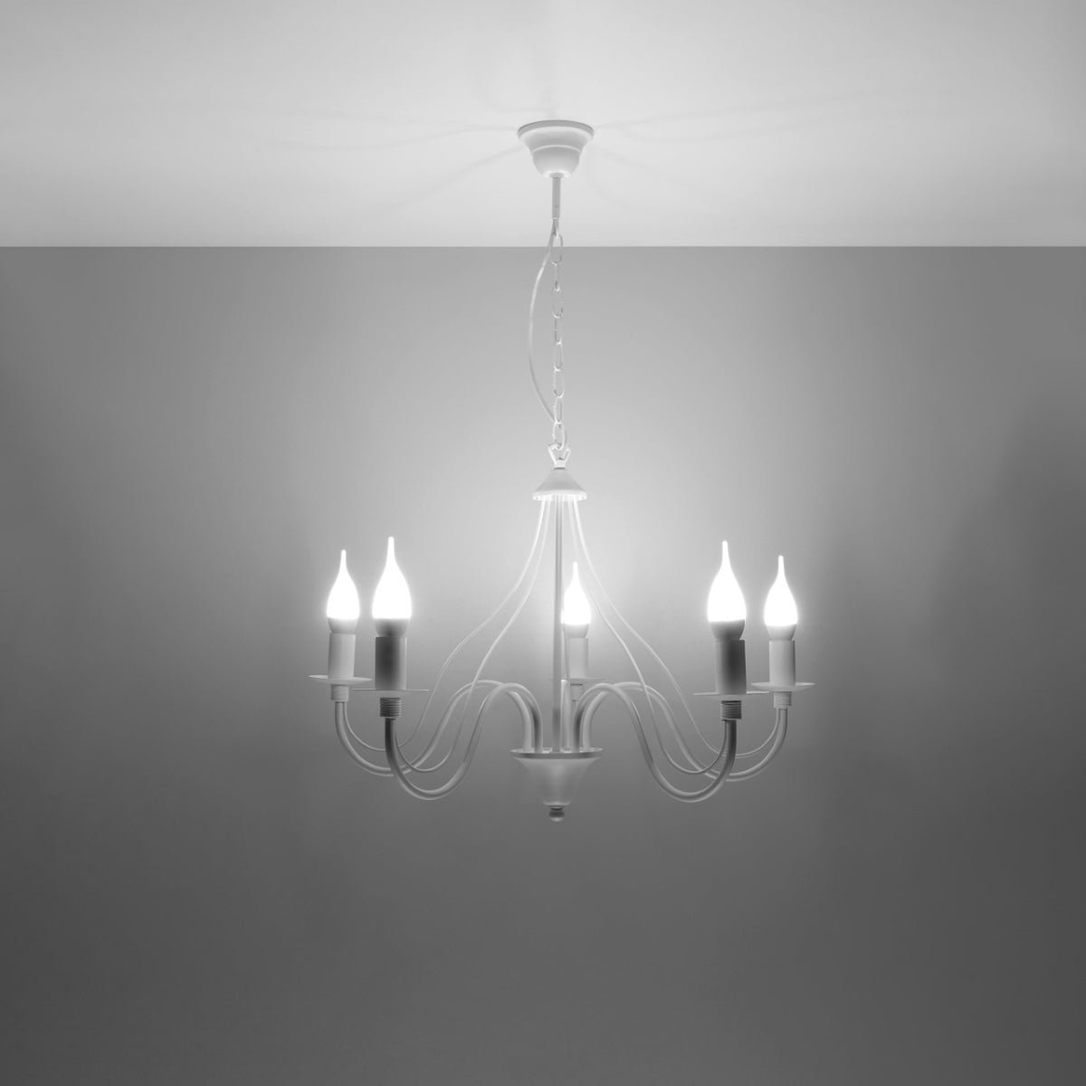 Lustre blanc allumé, cinq ampoules bougies diffusent une lumière vive sur fond gris sombre.