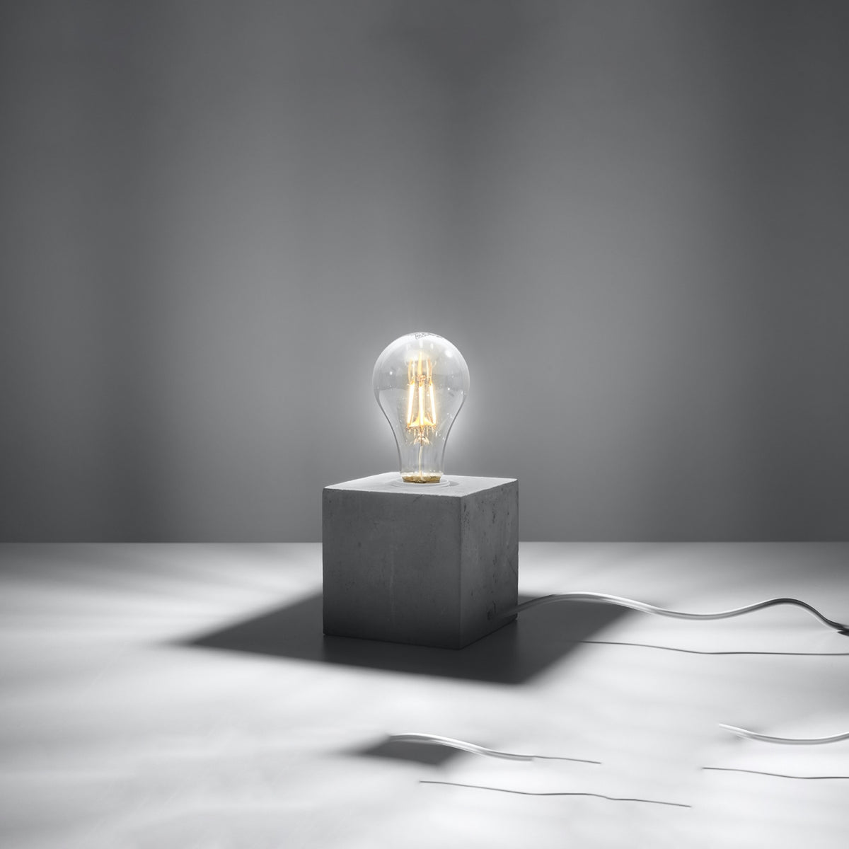 Mise en ambiance sombre, ampoule allumée éclairant légèrement le cube de béton
