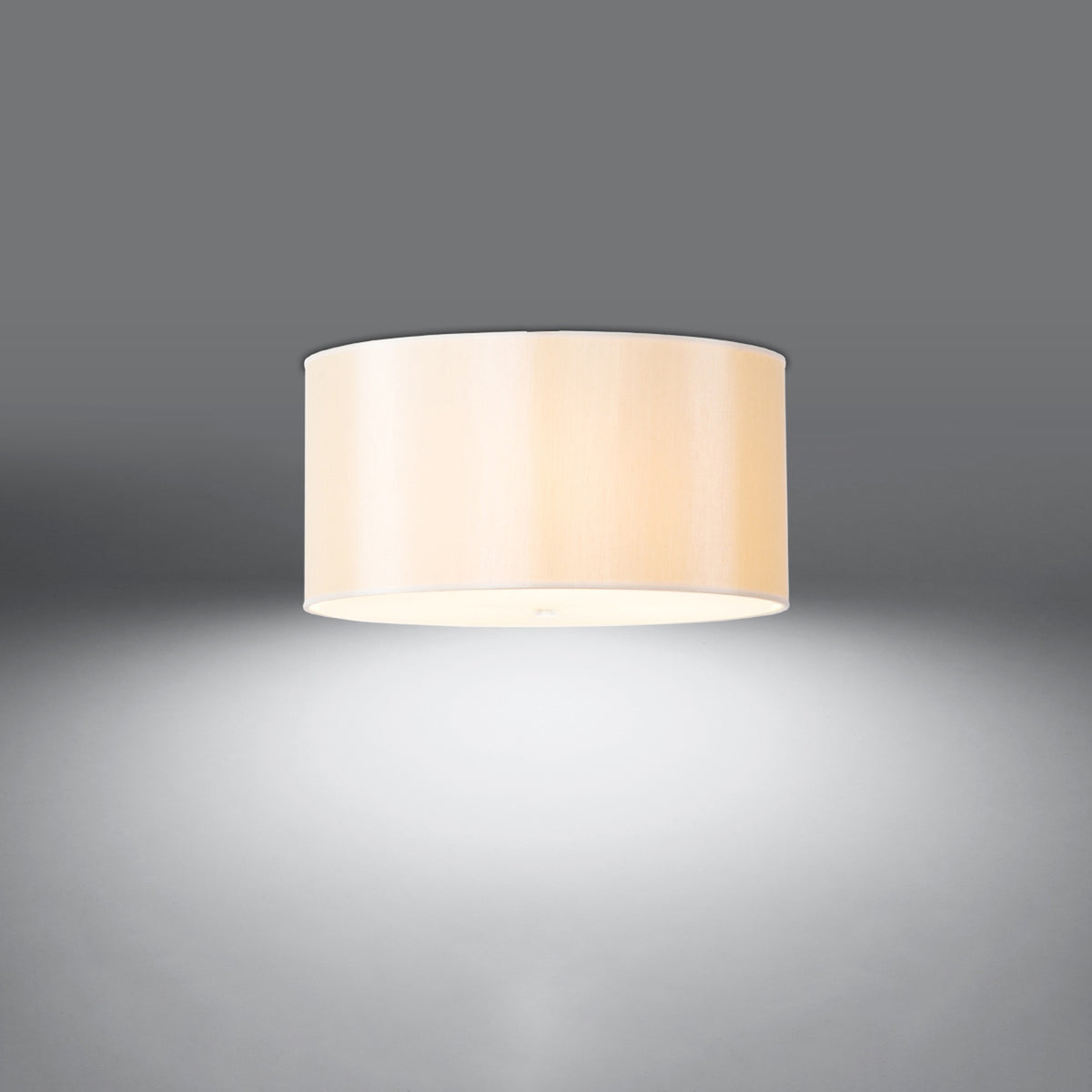 Luminaire blanc allumé au plafond, halo de lumière diffuse dans une pièce grise.