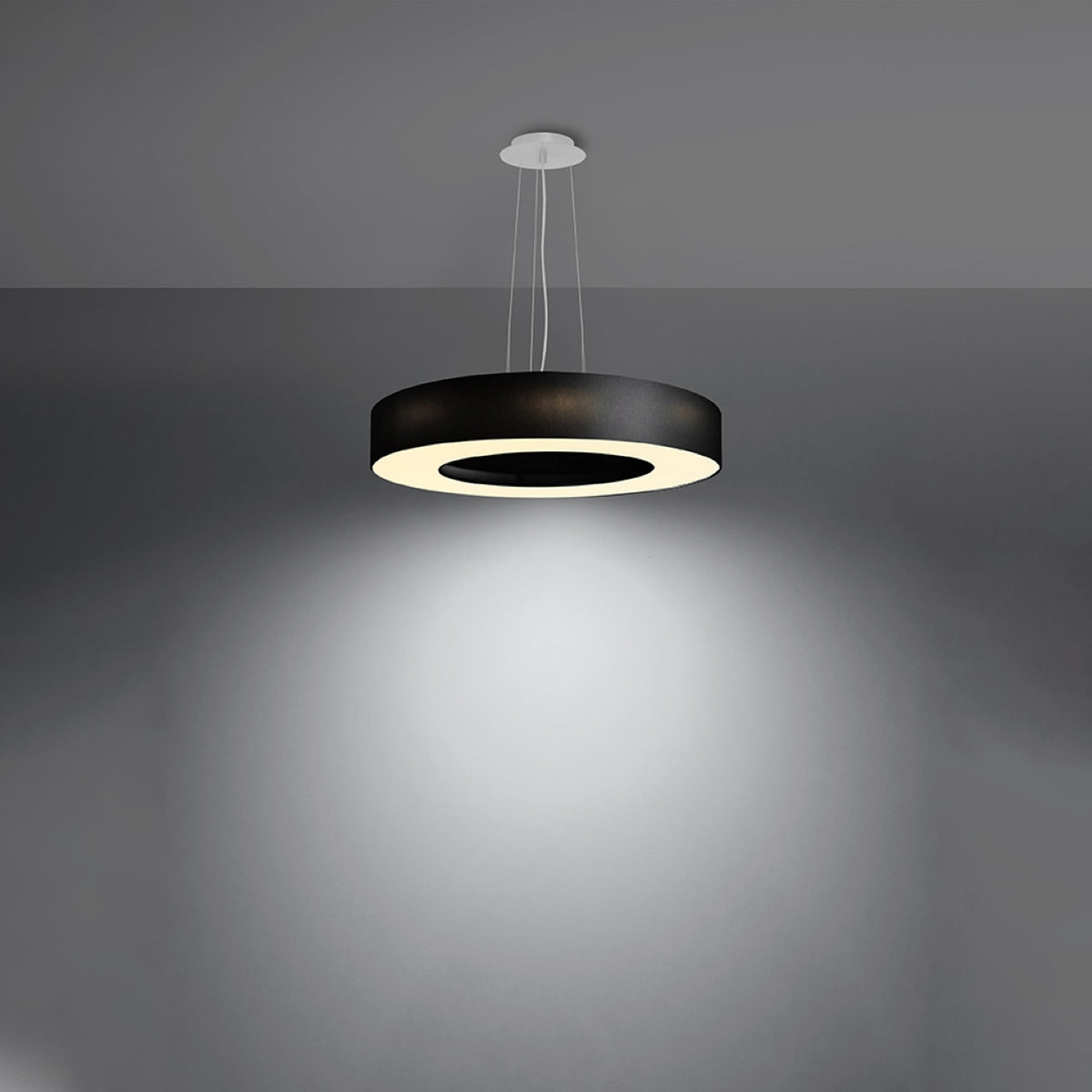 Luminaire suspendu allumé diffusant une lumière blanche dans une pièce sombre