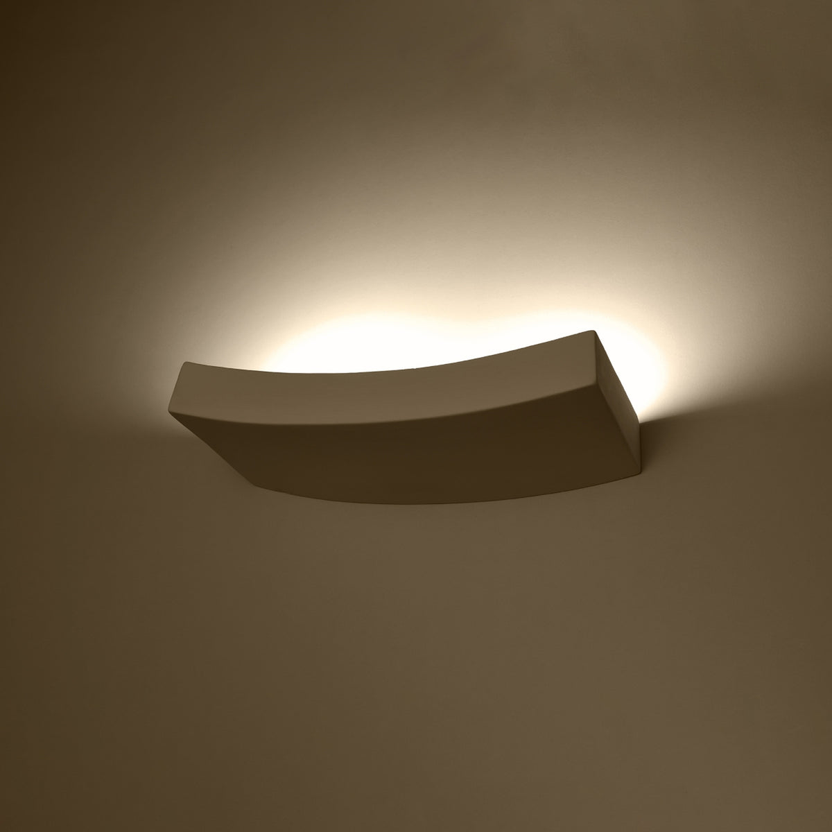 Applique allumée sur un mur, halo de lumière chaude diffusée vers le haut et le bas
