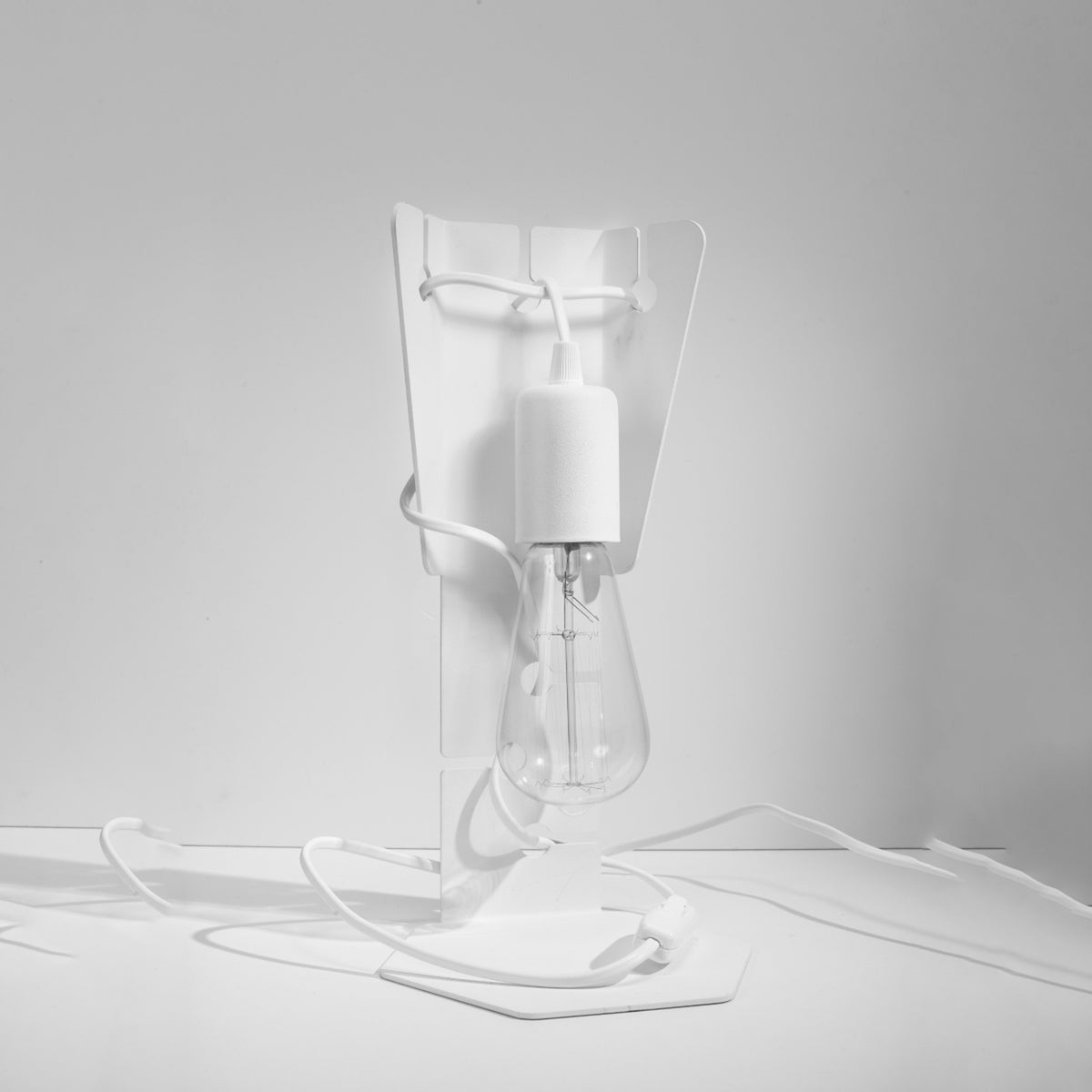 Même lampe blanche photographiée de face sur fond gris clair studio