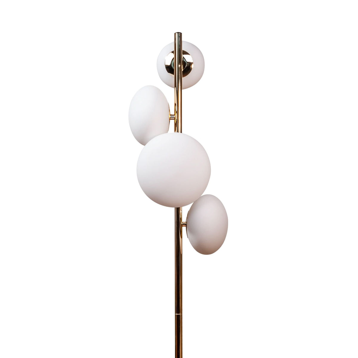 Détail du haut du lampadaire : tige dorée et quatre globes blancs suspendus à des supports.