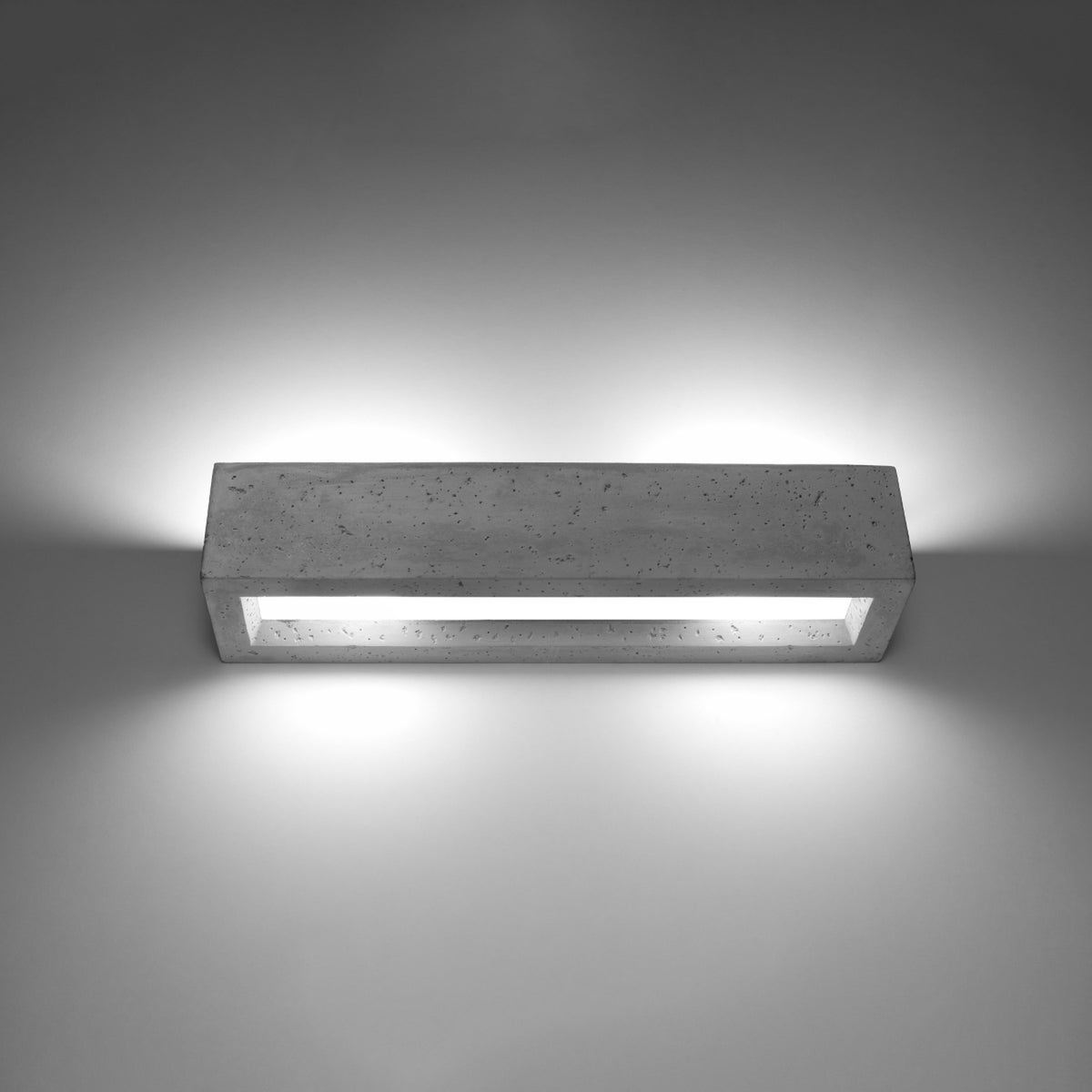 Applique allumée sur un mur, halo lumineux diffusé vers le haut et le bas.