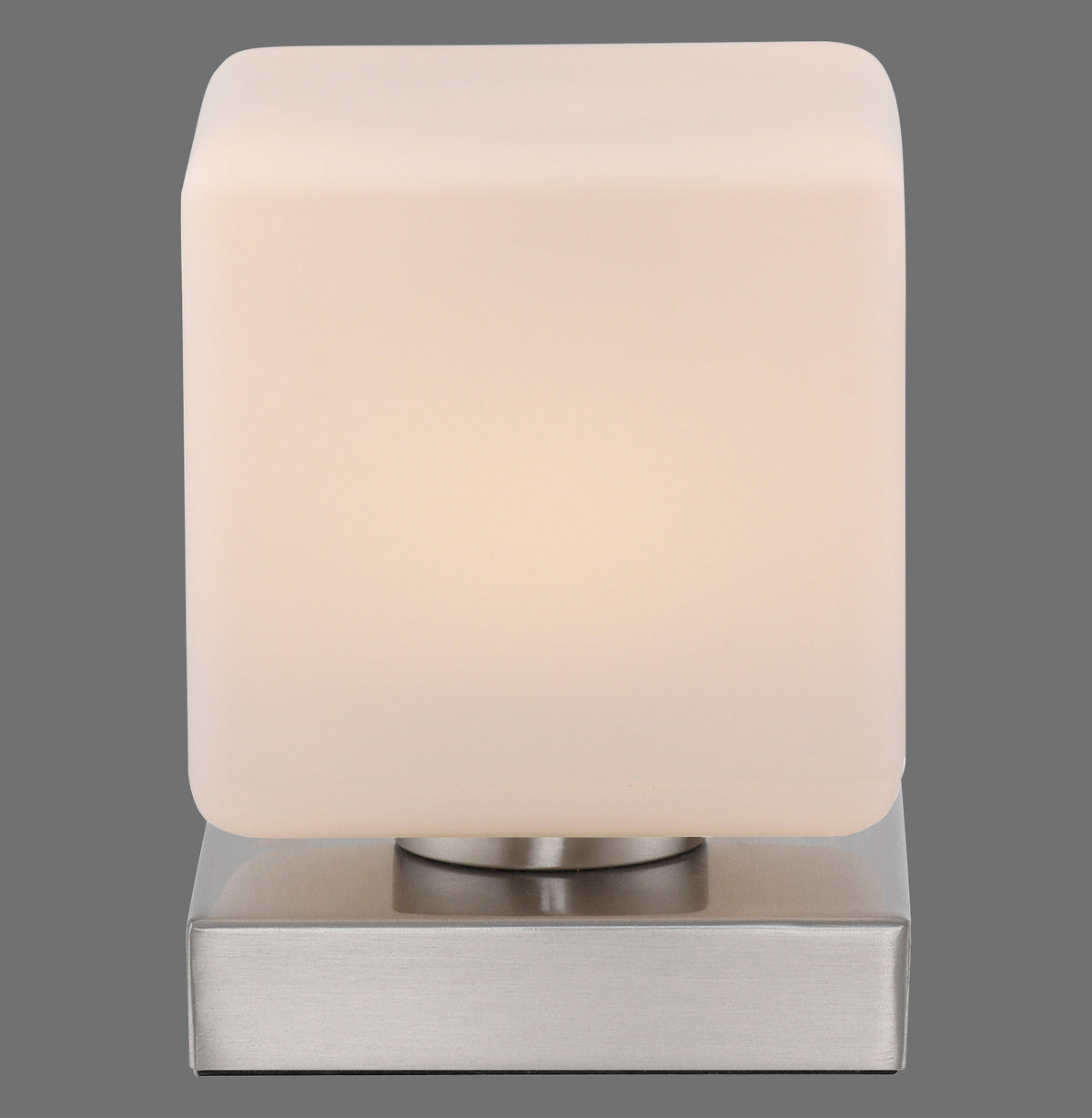 Vue de face du luminaire : abat-jour cubique en verre opalin allumé sur socle carré argenté