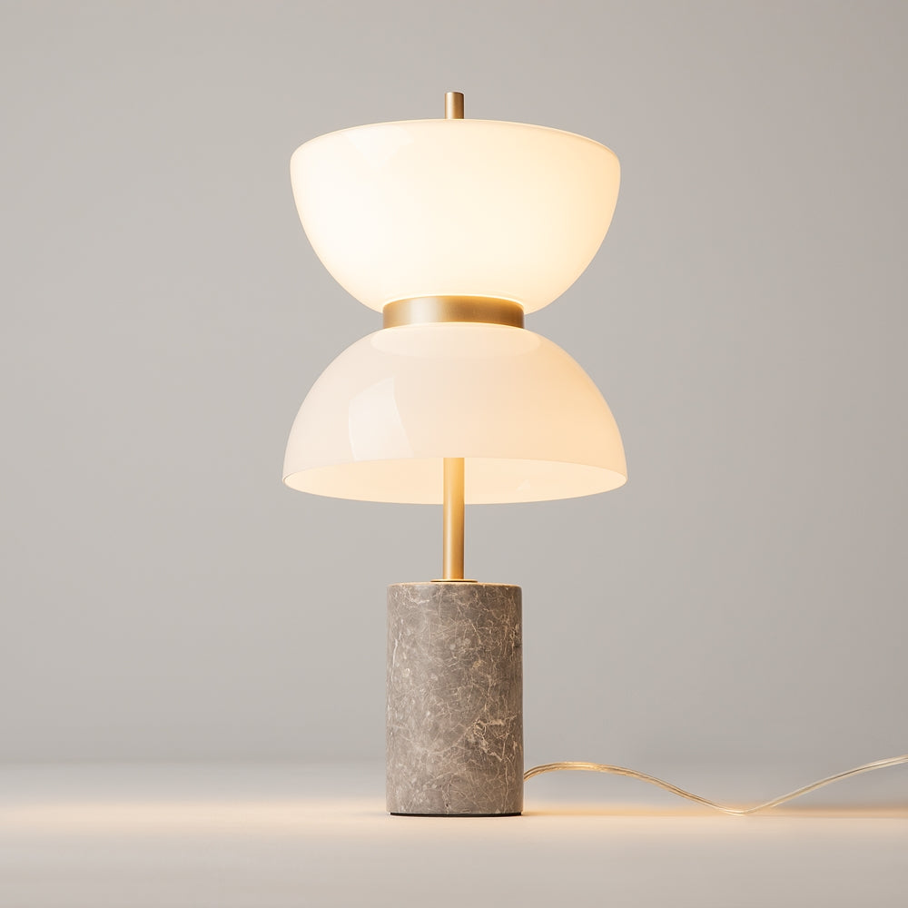 Lampe allumée sur fond gris, lumière chaude et câble transparent au sol