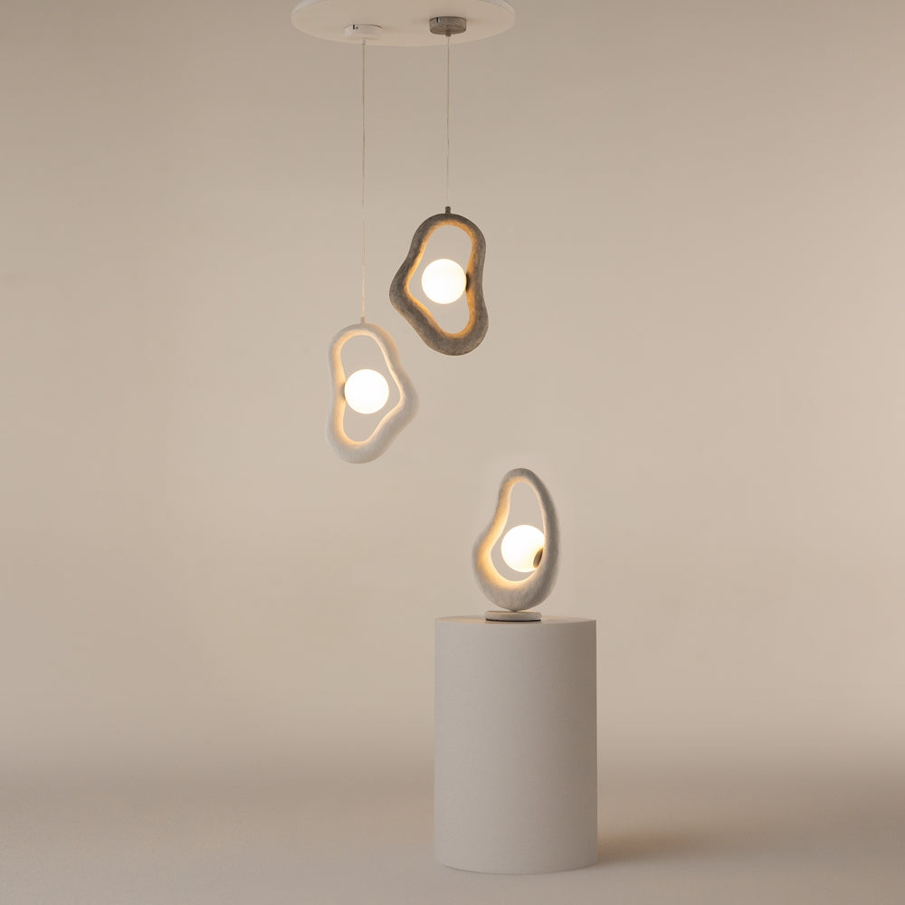 Mise en ambiance : deux suspensions et une lampe posée sur socle blanc.