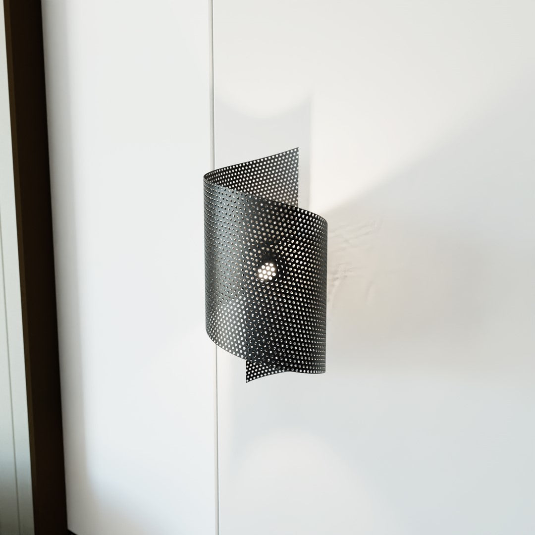 Applique fixée sur un panneau blanc et allumée, halo lumineux à travers la perforation.