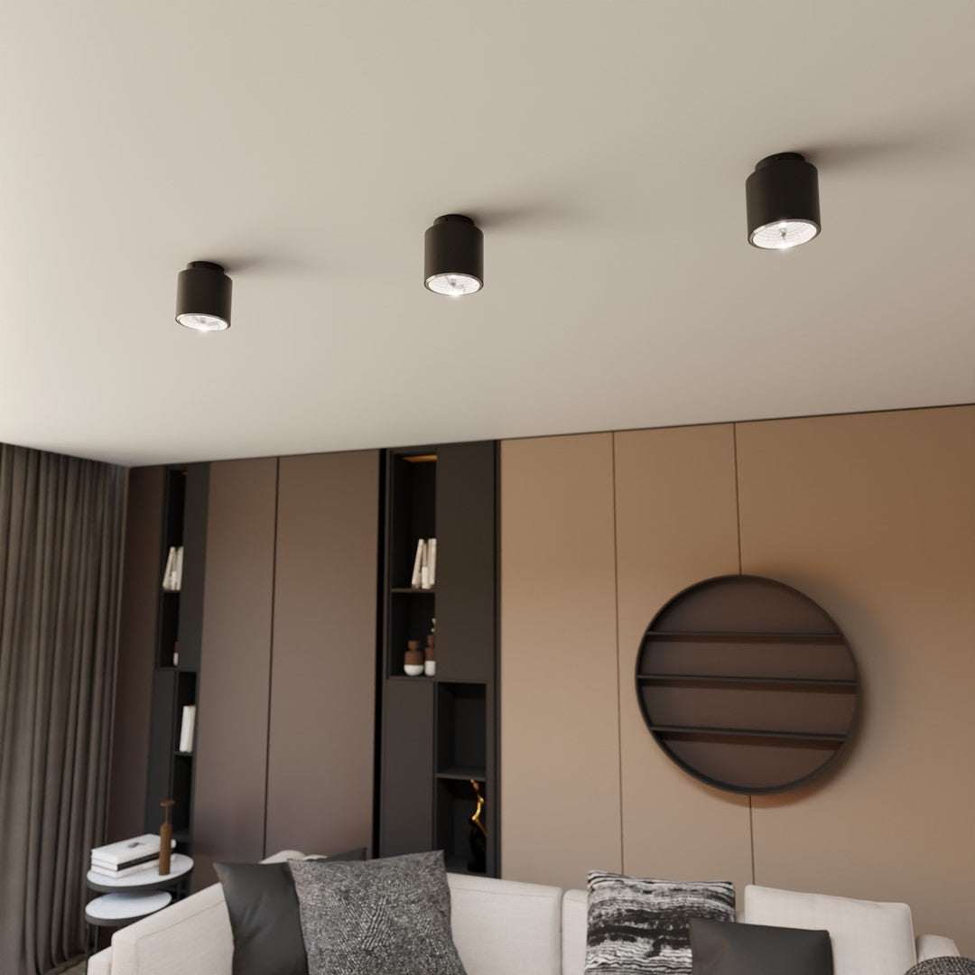 Trois plafonniers noirs alignés au plafond d'un salon moderne beige.