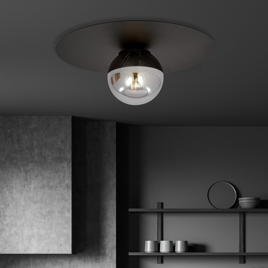 Plafonnier noir allumé au plafond dans une ambiance sombre avec étagères et objets.