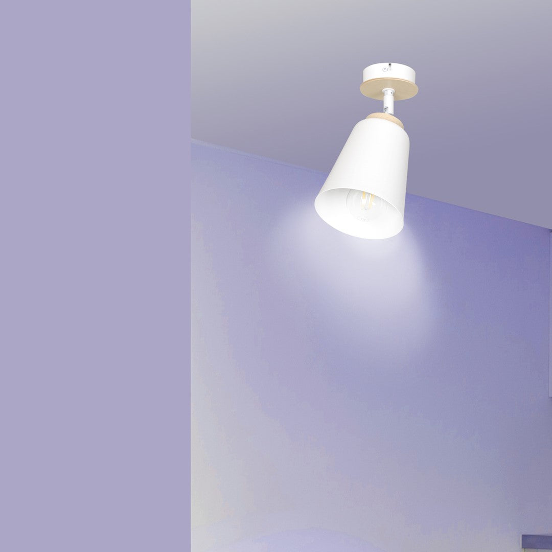 Plafonnier allumé fixé au plafond blanc devant un mur aux reflets mauves