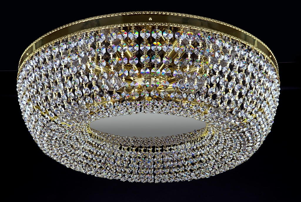 Plafonnier rond en cristal vu de face sur fond noir, monture dorée apparente