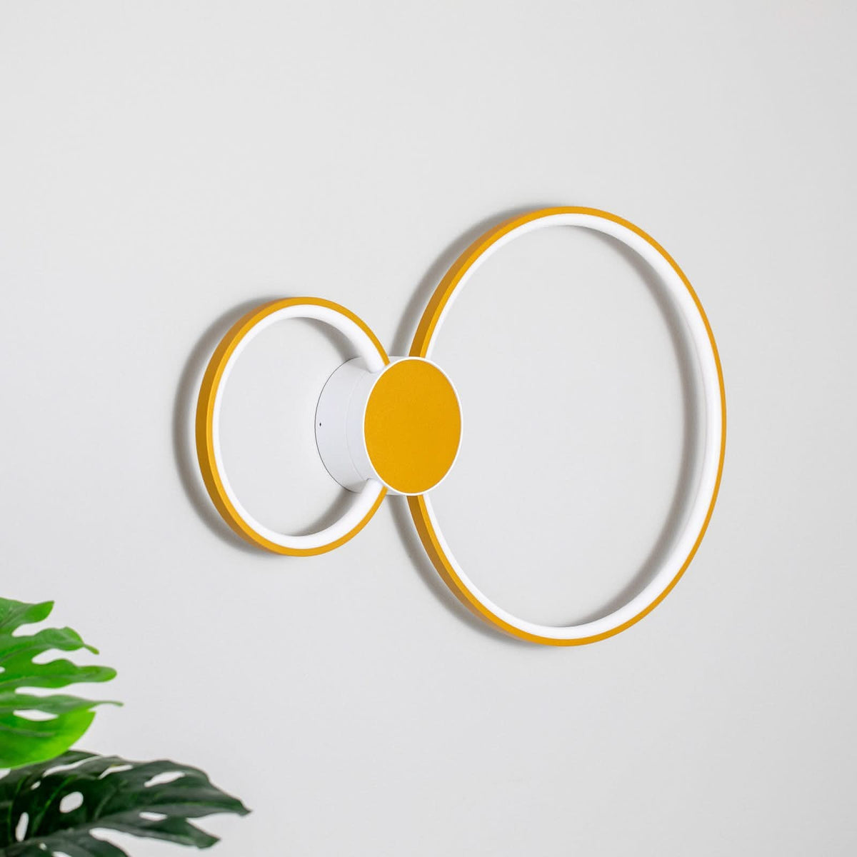 Applique murale LED double anneau éteinte sur fond clair, reflets et ombres douces