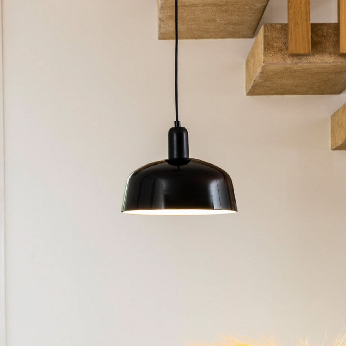 Suspension noire en verre, vue rapprochée sous une étagère en bois.