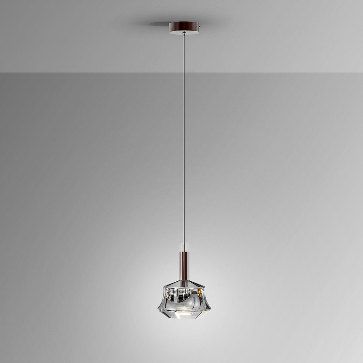 Suspension seule sur fond gris clair, verre facetté et tige bronze brossé.