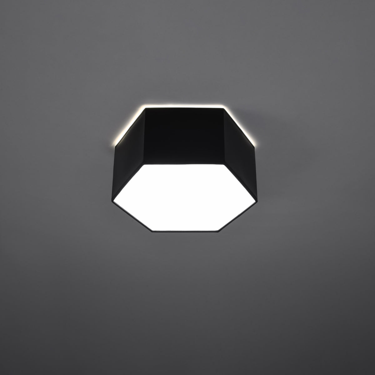 Vue de face du plafonnier allumé, halo lumineux sur fond gris foncé
