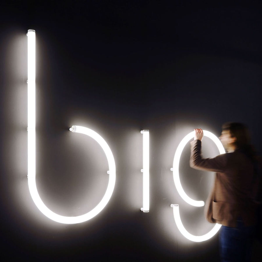 Personne ajustant les lettres lumineuses glob sur un mur sombre.
