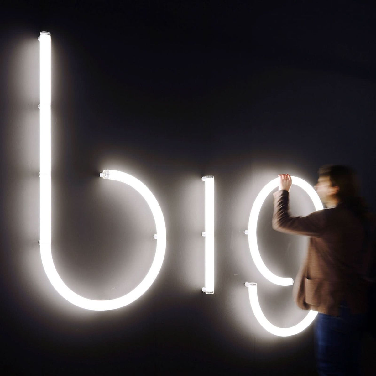 Personne installant les grandes lettres lumineuses bio sur un mur noir