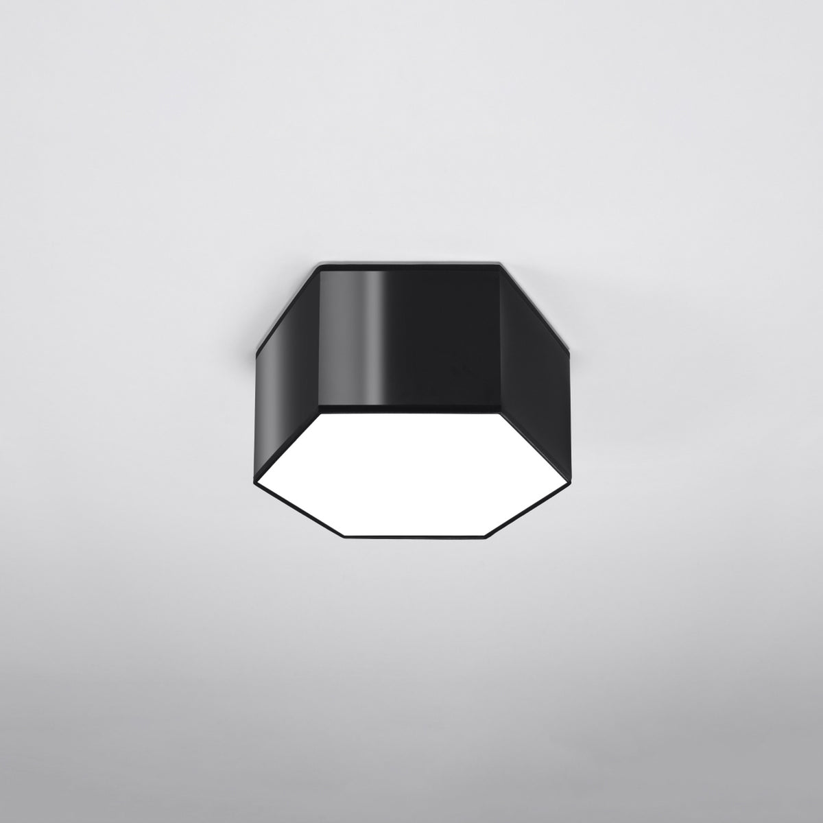 Luminaire hexagonal noir fixé au plafond, allumé, vu de face