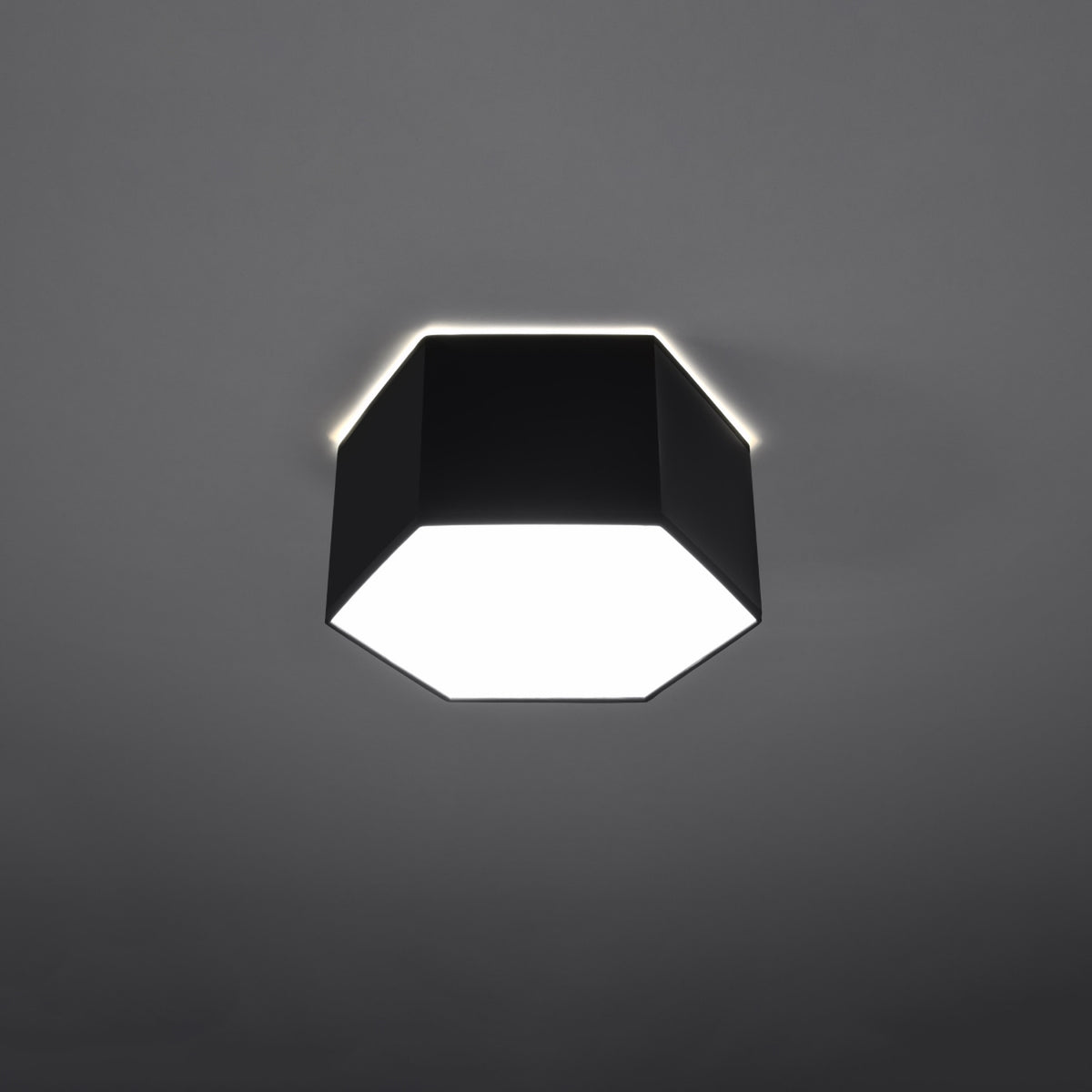 Luminaire allumé dans ambiance sombre, halo lumineux projeté au plafond