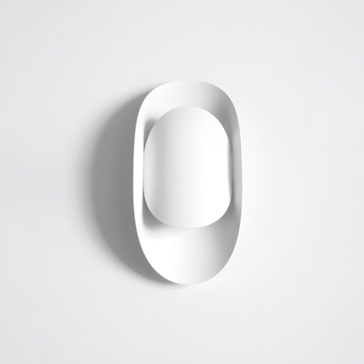Vue en angle du luminaire blanc, ombre portée révélant sa profondeur et son galbe