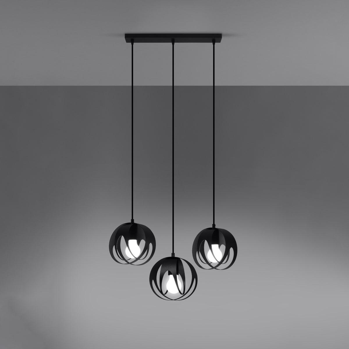 Suspension noire allumée, trois globes ajourés diffusant une lumière chaude sur fond gris