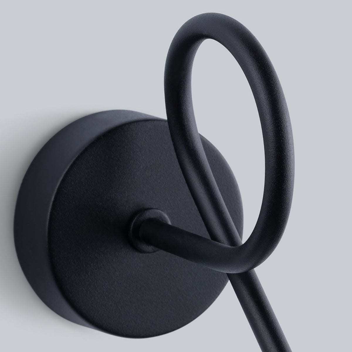 Détail de la platine ronde et du départ du bras formant une boucle en métal noir.