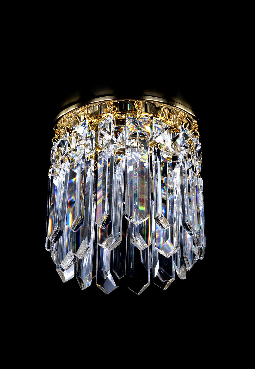 Spot plafonnier en cristal monté sur cercle doré, prismes transparents suspendus sur fond noir.