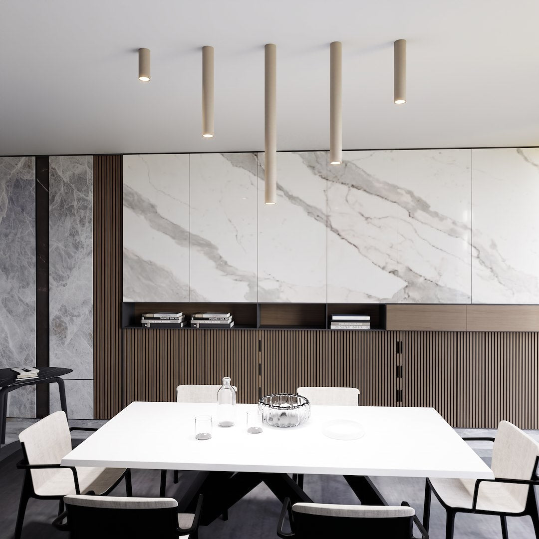 Mise en ambiance, cinq plafonniers cylindriques beige de longueurs différentes au-dessus d'une table.