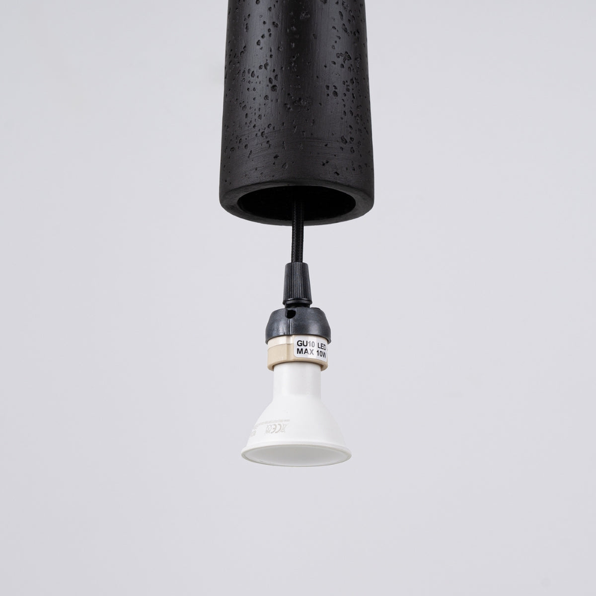 Détail de la douille GU10 avec ampoule retirée et câble textile tressé.