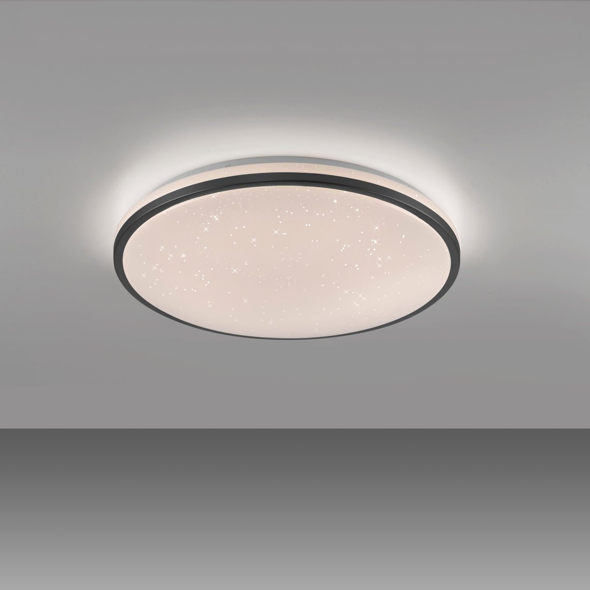 Plafonnier rond installé au plafond dans une pièce grise, lumière allumée.