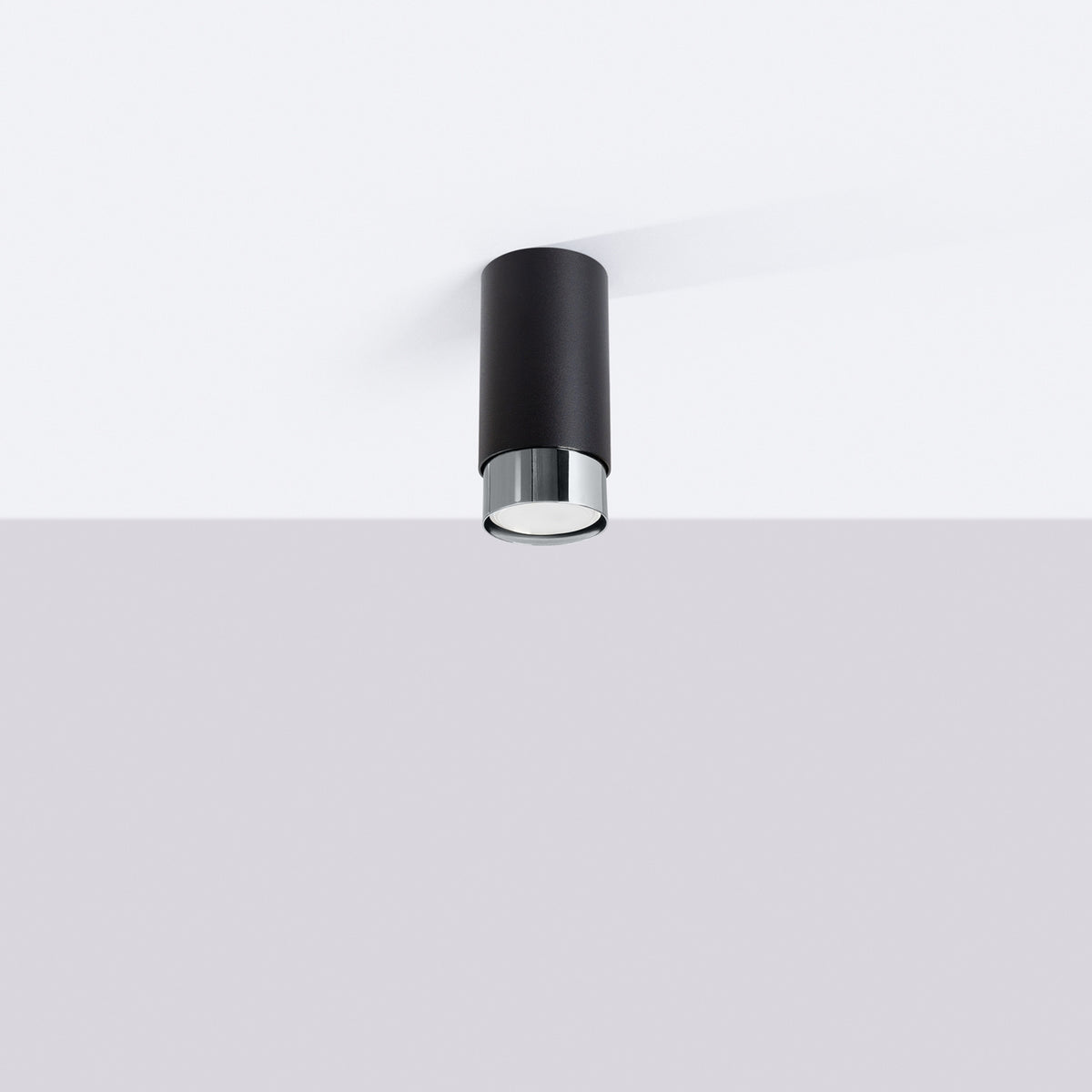 Luminaire cylindrique monté au plafond blanc, vu de dessous en situation.