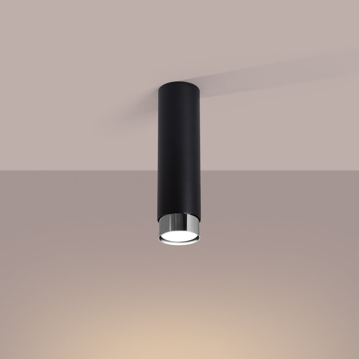 Plafonnier cylindrique noir et chromé monté au plafond beige, lumière chaude allumée.
