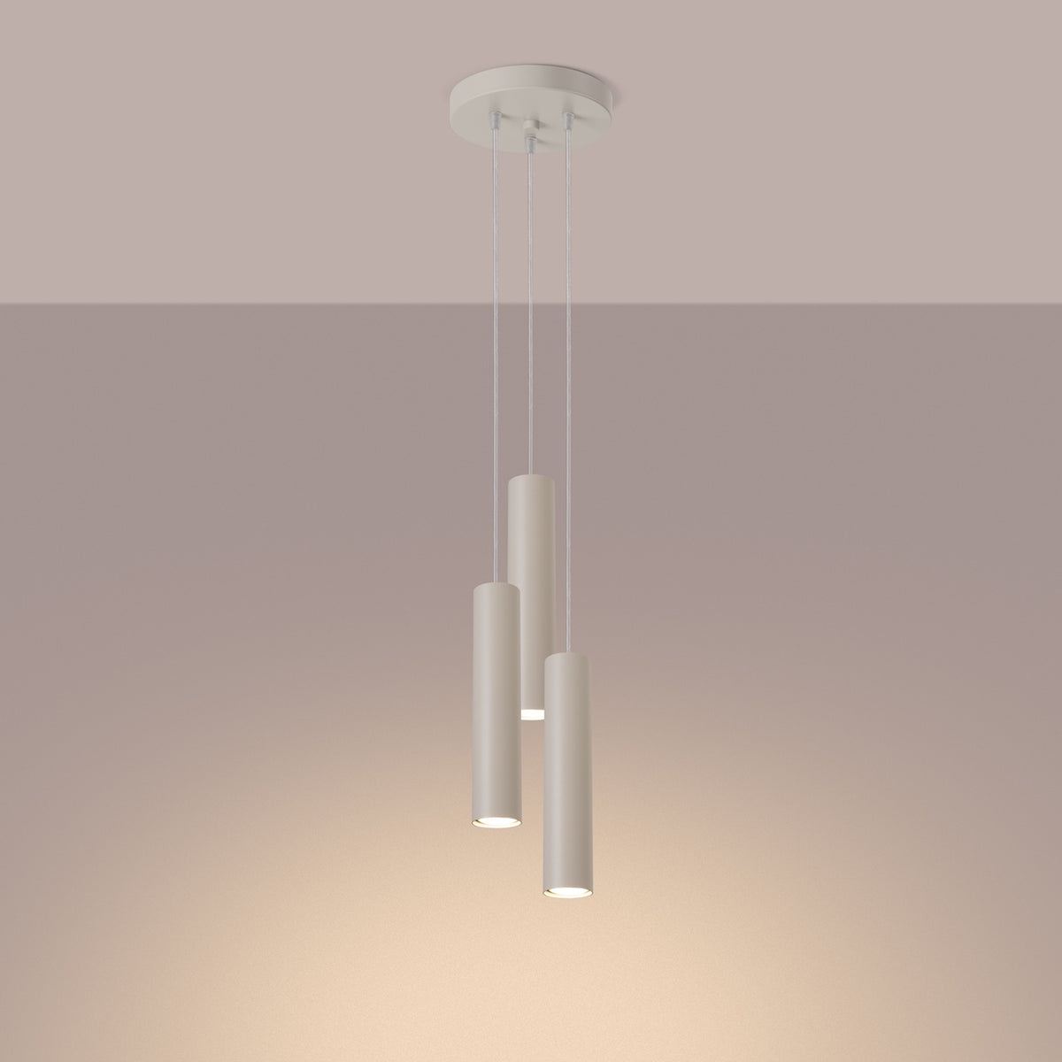 Mise en ambiance chaude montrant les trois cylindres suspendus éclairant le mur beige.