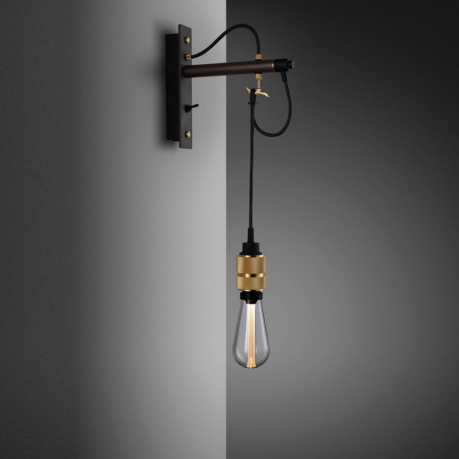 Détail de l'applique au bras tubulaire noir, douille dorée et ampoule Edison allumée