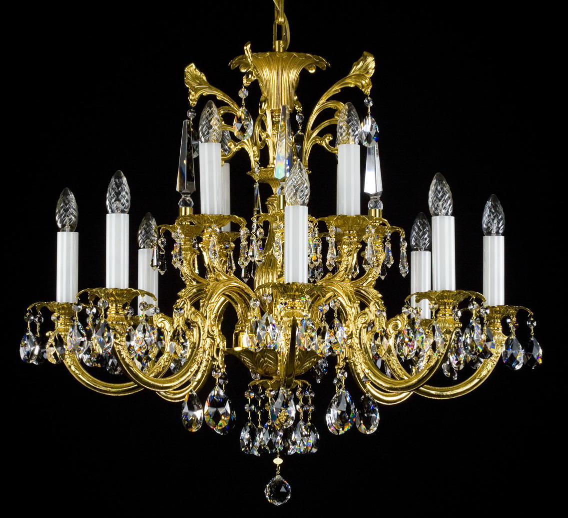 Lustre doré à bras ornés de pampilles en cristal, photographié de face sur fond noir.