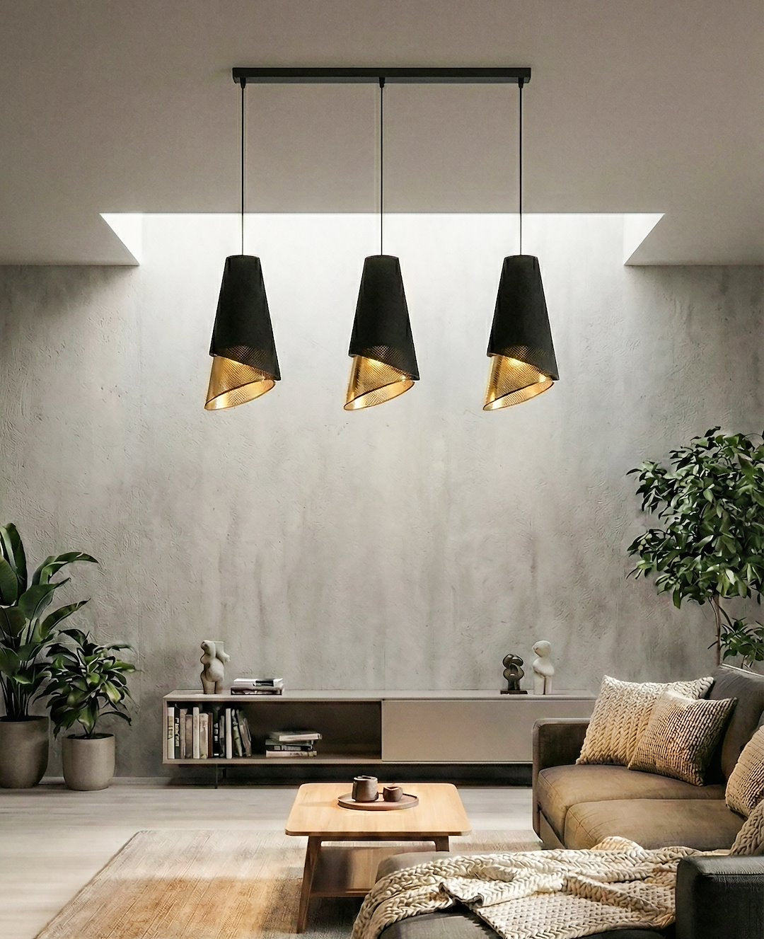 Mise en ambiance : trois suspensions noires et dorées éclairant un salon béton minimaliste.