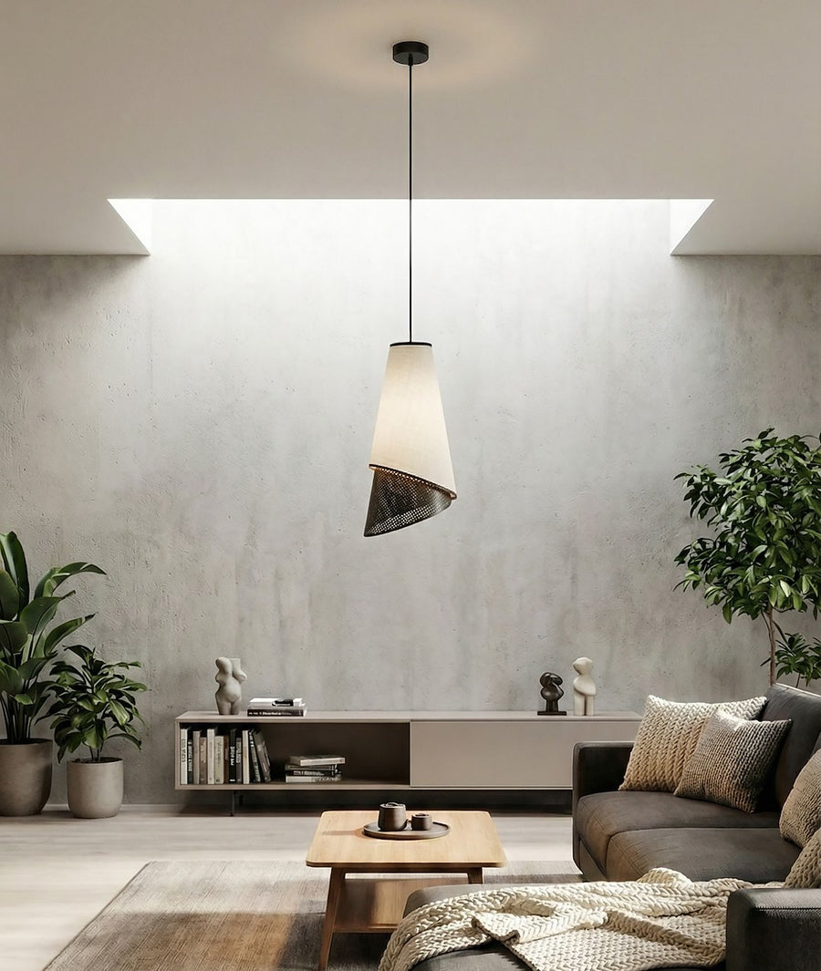 Pièce à vivre béton, suspension au-dessus table basse, canapé et plantes vertes.