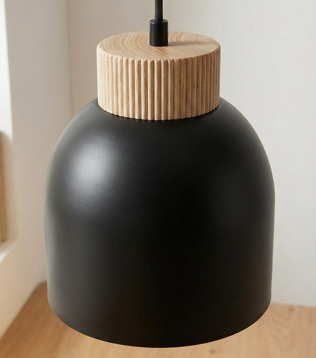 Plan rapproché du luminaire, abat-jour noir mat et couronne en bois tourné