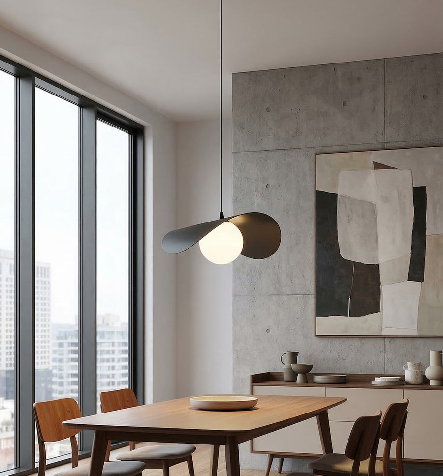Salle à manger en béton brut, suspension noire au-dessus d'une grande table en bois