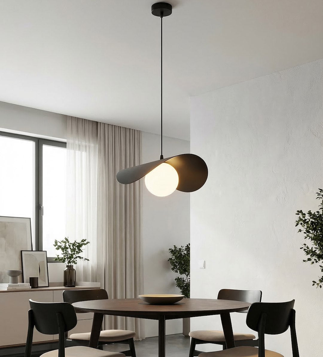 Pièce à vivre blanche, suspension allumée éclairant une table ronde en bois foncé