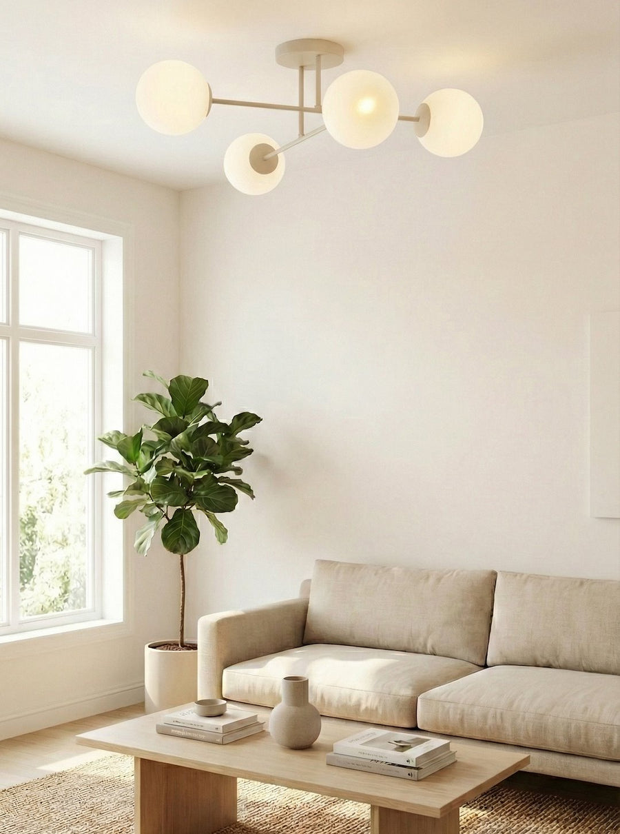 Luminaire allumé au plafond d'un salon beige avec canapé, plante verte et fenêtre