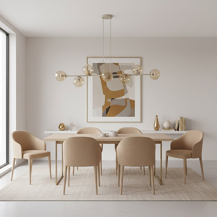 Luminaire suspendu au-dessus d'une table de salle à manger, chaises beiges et tableau encadré.