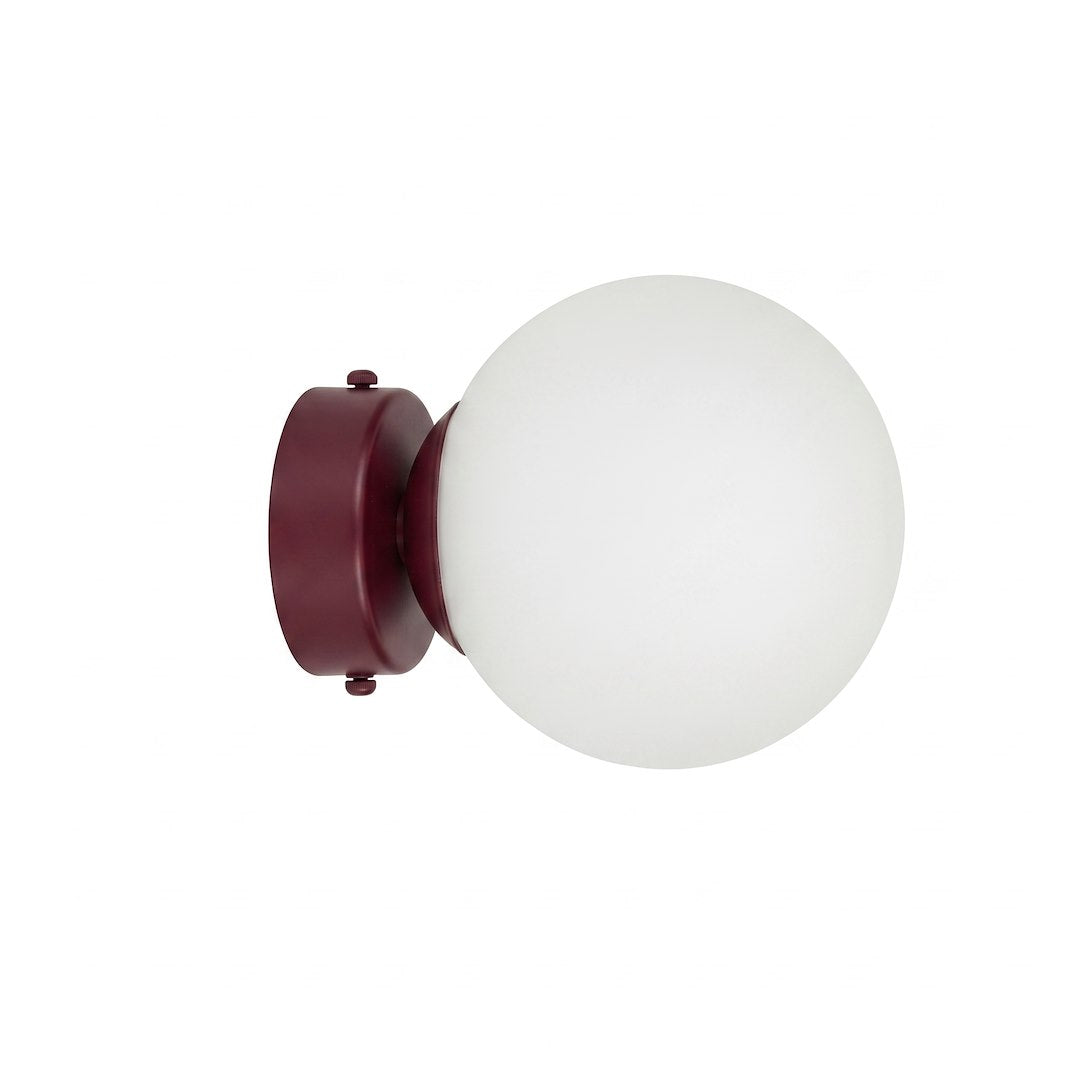 Applique murale de face sur fond blanc, globe en verre opalin et base bordeaux.