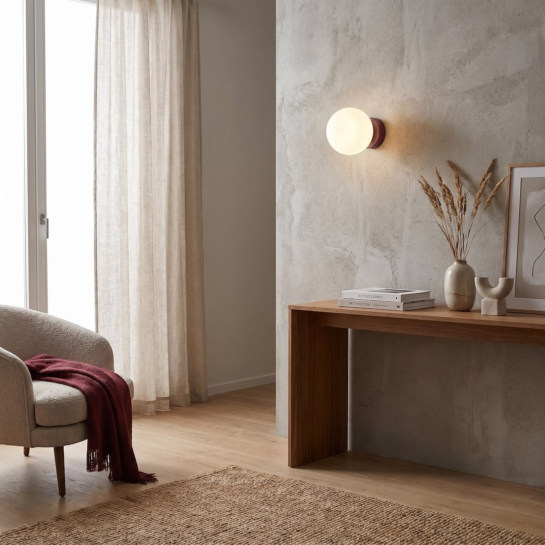 Mise en ambiance dans un salon, applique allumée au-dessus d'une console en bois.