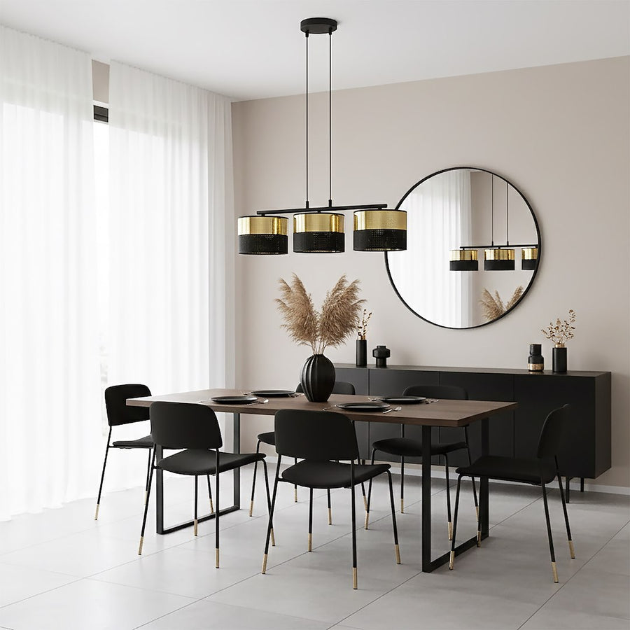 Pièce claire avec miroir rond, reflet du luminaire noir et doré au-dessus du repas.