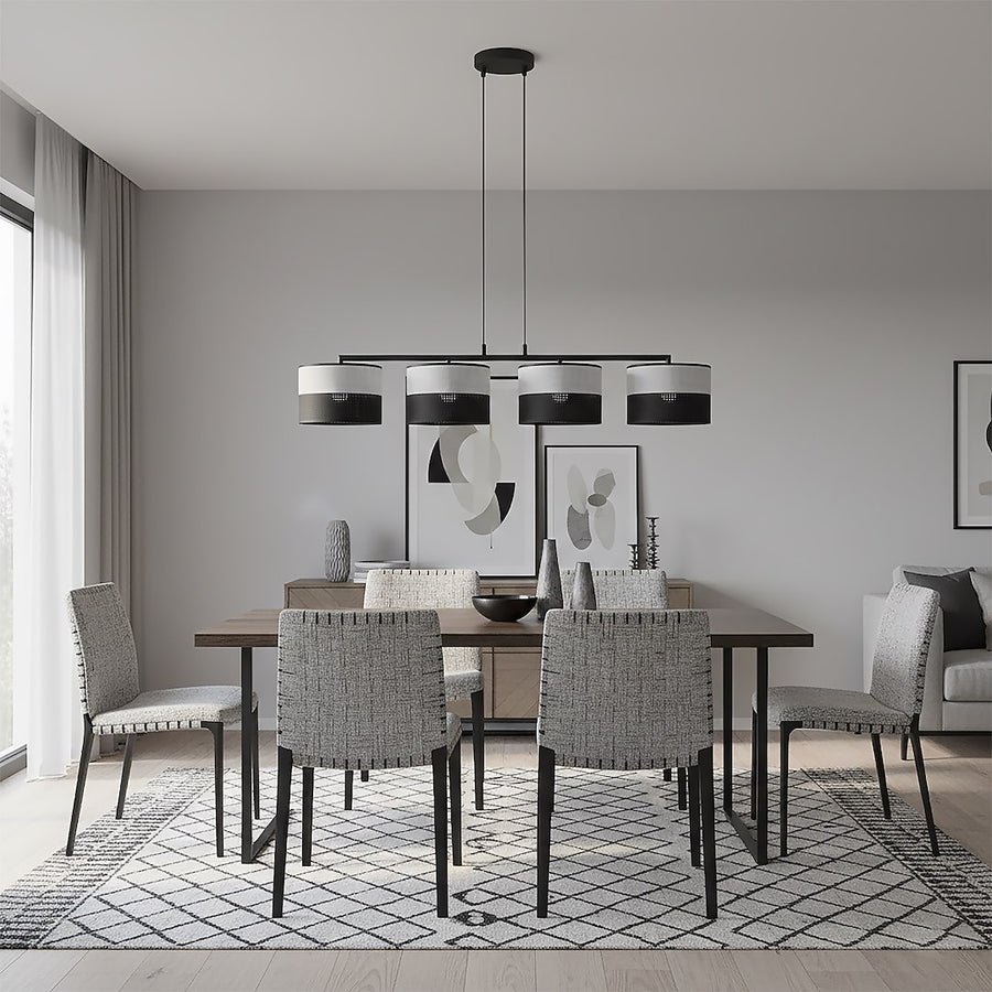 Suspension installée au-dessus d'une table de salle à manger avec chaises et tapis graphique.
