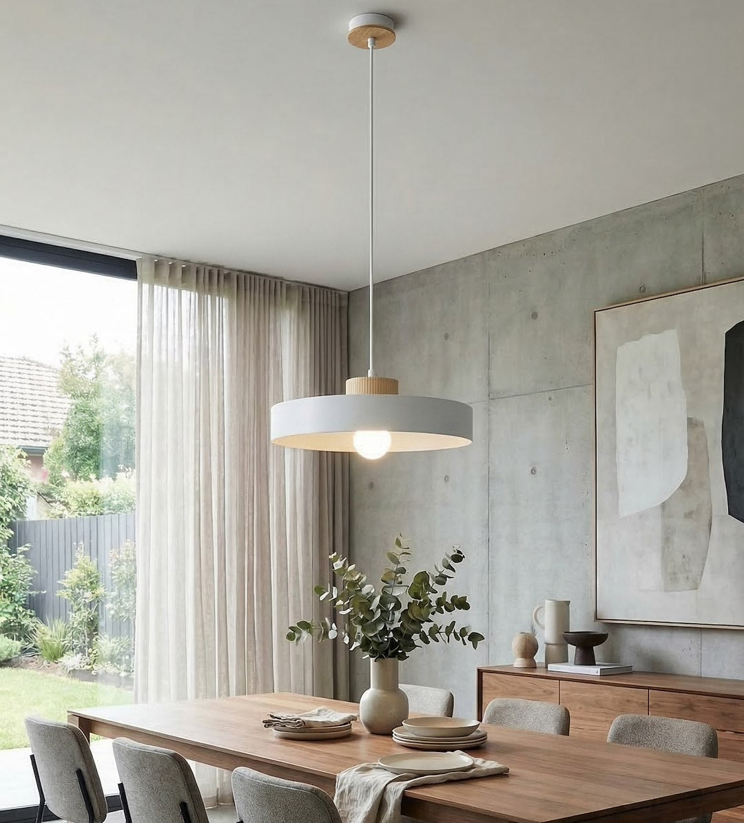 Ambiance salle à manger en béton, suspension éclairant une grande table en bois